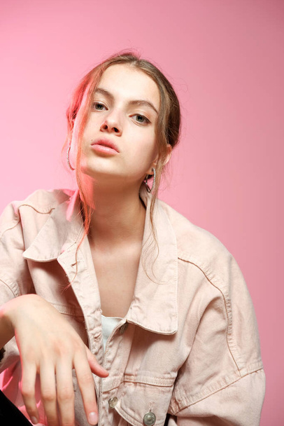 A girl in a pink denim shows different emotions and poses on a pink background. - Foto, imagen