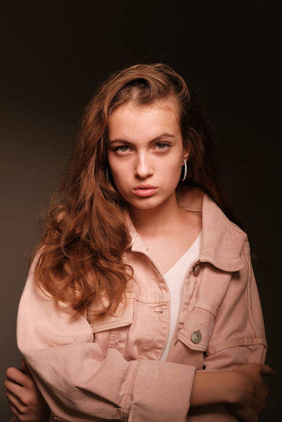 Girl in a pink jacket poses on a dark background. Fashion photography concept - Photo, image