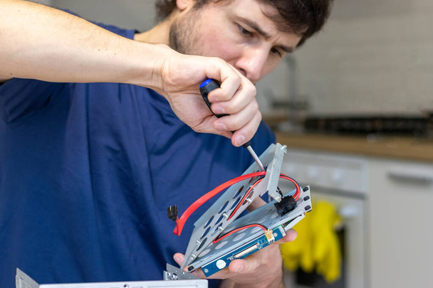 Mladý muž sestavuje elektronické počítačové komponenty vlastníma rukama. Hobby, technik, do-it-yourself montáž a vynález technologie - Fotografie, Obrázek