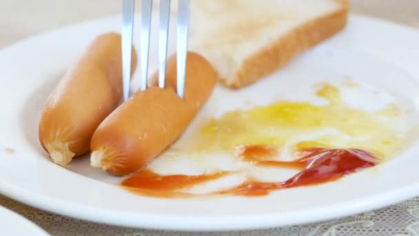 Asiatin isst Wurst mit Ketchup. Amerikanisches Frühstück mit Spiegeleiern und Toast. - Filmmaterial, Video