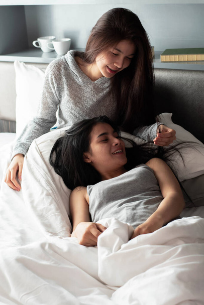 Kaksi kaunista naista istuu sängyllä, makea ja romanttinen tunne, tekee toimintaa yhdessä, aamulla, hyvä suhde, paras huonetoveri. - Valokuva, kuva