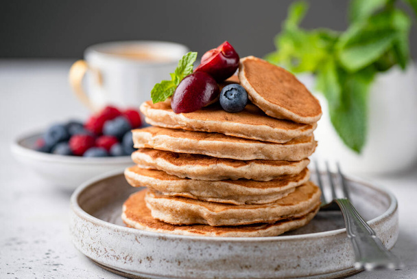 Vegan gluten free buckwheat pancakes with berries on a plate. Healthy pancakes - Фото, изображение
