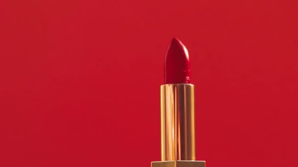 Κόκκινο κραγιόν σε χρυσό σωλήνα και λαμπερό φως φωτοβολίδες, πολυτελή προϊόντα μακιγιάζ και καλλυντικά διακοπών για το εμπορικό σήμα ομορφιάς - Πλάνα, βίντεο