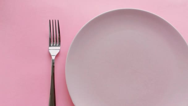 Rózsaszín asztal beállítása bazsarózsa virágok a tányéron és evőeszközök luxus vacsora, esküvő vagy születésnapi ünnepség - Felvétel, videó