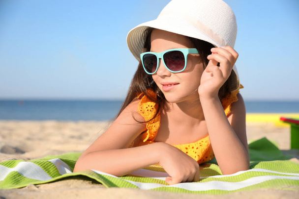 Cute little child lying at sandy beach on sunny day - Foto, immagini