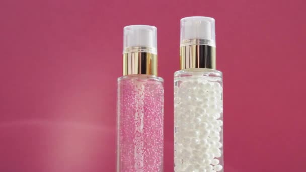 Prodotti di lusso per la cura della pelle e brillanti razzi leggeri su sfondo rosa, base per il trucco e gel siero come routine di cura della pelle per cosmetici per il viso e marchio di bellezza - Filmati, video