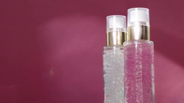 Luxe huidverzorgingsproducten en glanzende lichtflares op roze achtergrond, make-up basis en serum gel als huidverzorgingsroutine voor gezichtscosmetica en beauty merk - Video