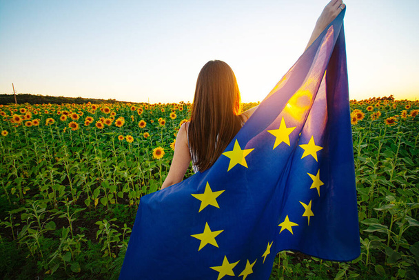Girl with the European Union flag against the sunflowers field - 写真・画像