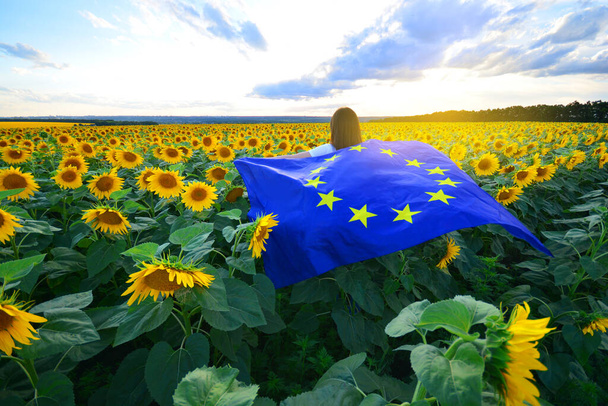 European Union flag in female hands against the sunflowers field - Photo, Image