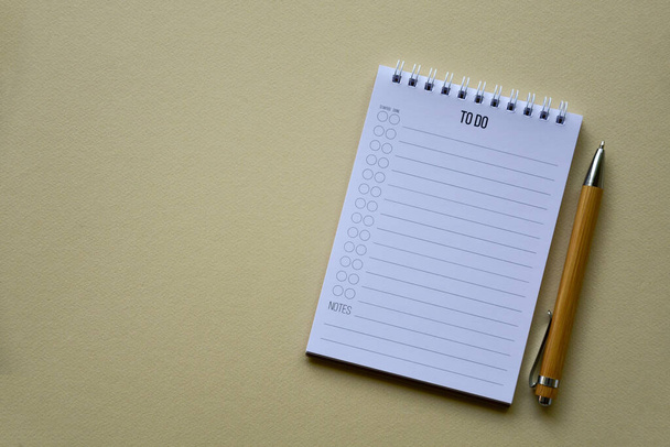 Notepad with wooden pen on a beige paper background. Top view. Close-up. Flat lay. - Photo, Image