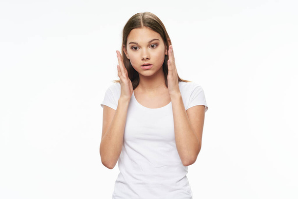  girl in a white T-shirt holds her hands near her face - Foto, Imagem