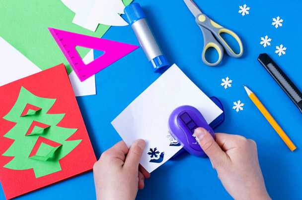 子供はクリスマスツリーでカードを作る。オリジナル子供アートプロジェクト。DIYのコンセプト。ステップバイステップの写真の指示。ステップ8 。雪片をカット - 写真・画像