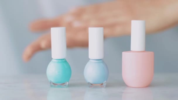 Жіночі руки та пляшки для нігтів, органічний косметичний продукт для французького манікюру, барвистий пастельний лак для нігтів на мармуровому столі, чудовий макіяж та бренд краси
 - Кадри, відео