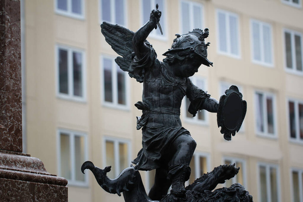 Zbliżenie starożytny posąg Putto zabijania diabła na piedestale Marian kolumna Marienplatz, Monachium, Niemcy, podróż tła - Zdjęcie, obraz