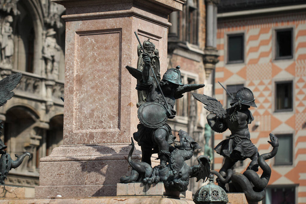 Zbliżenie starożytny posąg Putto zabijania diabła na piedestale Marian kolumna Marienplatz, Monachium, Niemcy, podróż tła - Zdjęcie, obraz