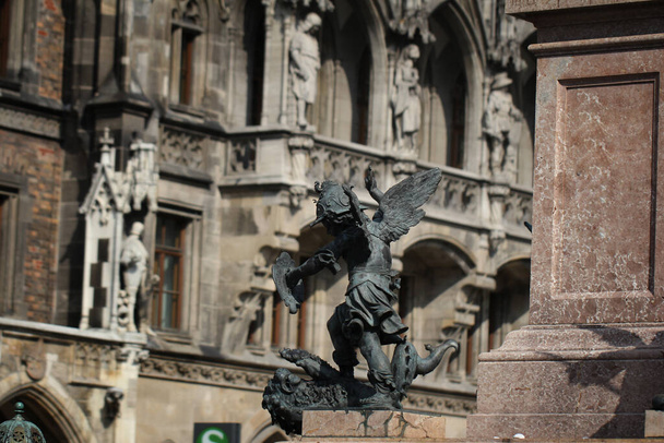 Крупным планом древняя статуя Путто убивает дьявола на пьедестале Марианской колонны в Мюнхене, Германия - Фото, изображение