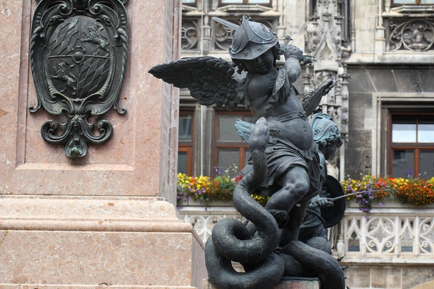 Close-up ancient statue of Putto killing devil at the Marian column's pedestal Marienplatz, Munich, Germany, travel destination backgrounds - Photo, Image