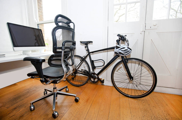 PC, scrivania e bicicletta all'interno di un ufficio - Foto, immagini