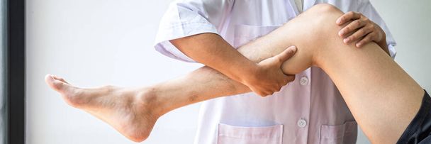 Arts of fysiotherapeut werken onderzoeken van de behandeling van gewonde been van atleet mannelijke patiënt, Doen van de revalidatie therapie pijn in kliniek. - Foto, afbeelding