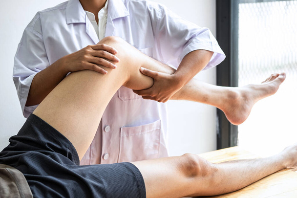 Vrouwelijke fysiotherapeut werken onderzoeken behandeling van gewonde been van mannelijke patiënt, Doen oefeningen de revalidatie therapie pijn zijn in kliniek. - Foto, afbeelding