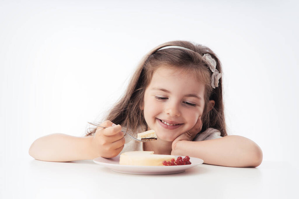 Schöne kleine Mädchen überrascht von einem leckeren Käsekuchen. Kind bereit, Kuchen zu essen.  - Foto, Bild