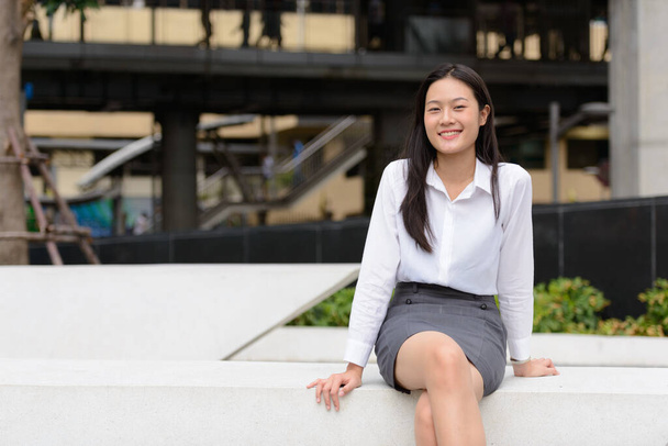 Portrait of young beautiful Asian businesswoman in the city streets outdoors - 写真・画像