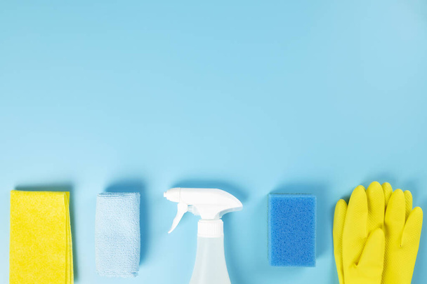 Detergents and cleaning products agent, sponges, napkins and rubber gloves, blue background. Top view. Copy space - 写真・画像