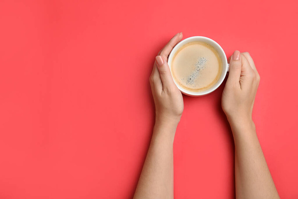 Woman with cup of coffee on red background, top view. Space for text - Photo, Image
