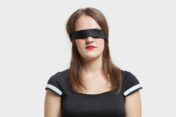 Young blindfolded woman against gray background - Foto, Bild