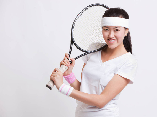 Beyaz arka planda raket tutan mutlu bayan tenisçinin portresi - Fotoğraf, Görsel