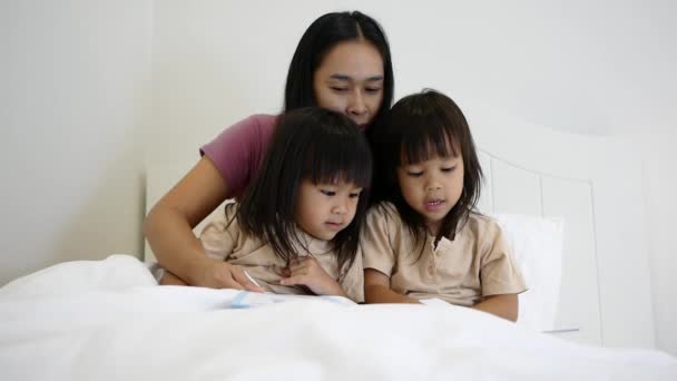 Mère lisant des histoires à l'enfant avant d'endormir ses filles. Heureux temps en famille. - Séquence, vidéo