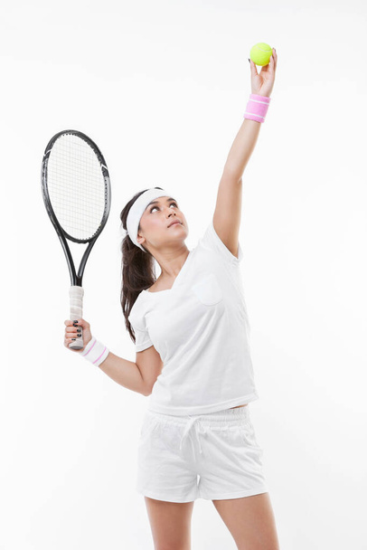 Young female tennis player preparing to serve ball against white background - Foto, immagini