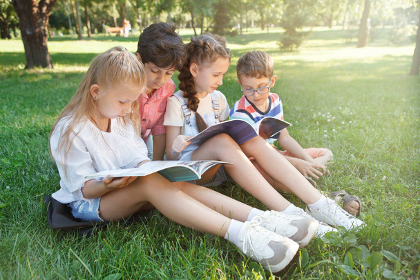 Schoolkids studying outdoors on the grass at ublic park - Φωτογραφία, εικόνα