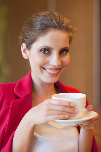 Portrait of a beautiful young woman holding coffee cup - Foto, imagen