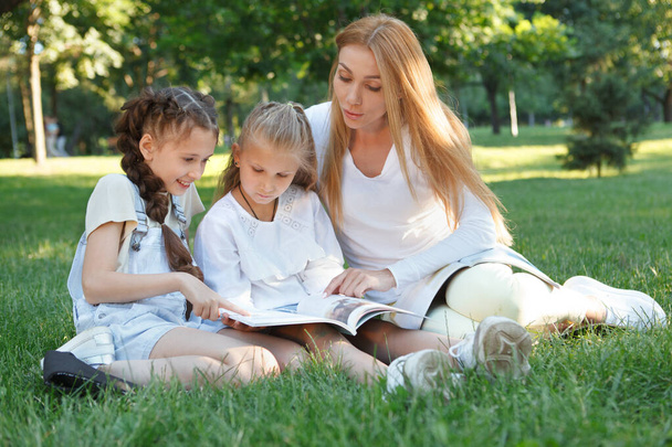 Дві маленькі дівчата насолоджуються уроком відкритого повітря в парку зі своїм улюбленим вчителем
 - Фото, зображення