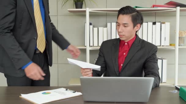 Een Aziatische kantoormedewerker heeft een brief ontvangen om hem te ontslaan. Hij is gestrest en geschokt omdat hij niet voorbereid is op de baan door gebrek aan inkomen.. - Video