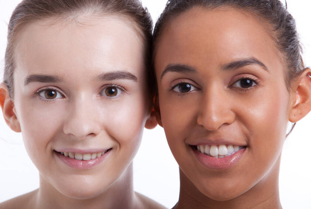 Portrait of two young female friends smiling together against white background - Fotografie, Obrázek