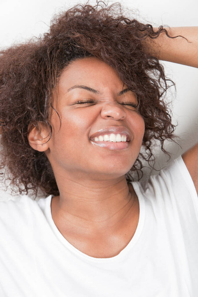 Excited young African American woman with hands in hair smiling against white background - Фото, зображення