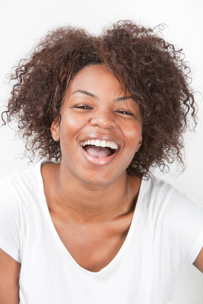 Portrait of a joyful African American young woman laughing against white background - Zdjęcie, obraz