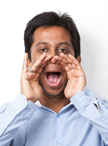 Portrait of young Indian man shouting against white background - Photo, image