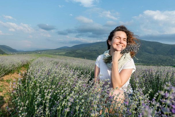 Beautiful girl on a lavender field enjoys the landscape and the smell - Photo, Image