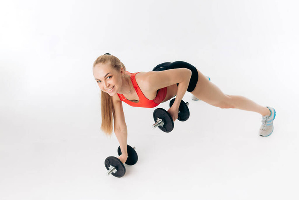 sporty woman doing press ups with dumbbells in the gym - Foto, Imagen