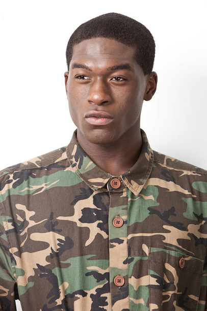 Thoughtful young military soldier in camouflage clothing looking away over white background - Foto, afbeelding