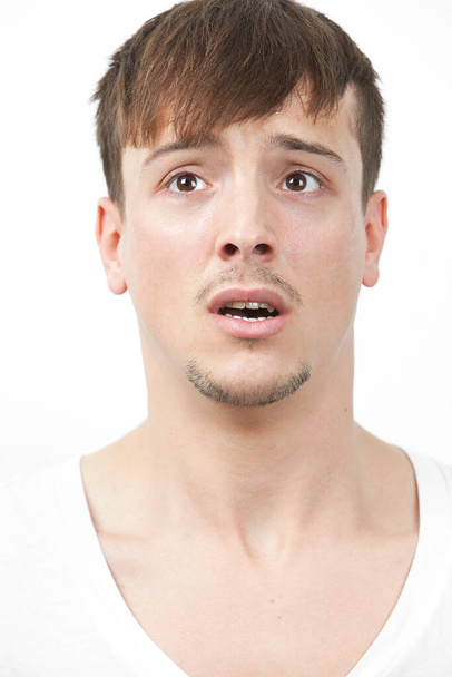Fearful young man looking away over white background - Foto, Imagem