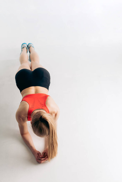 fit actiav egirl in sportswear is leaning on her elbows and doing exercises - Φωτογραφία, εικόνα