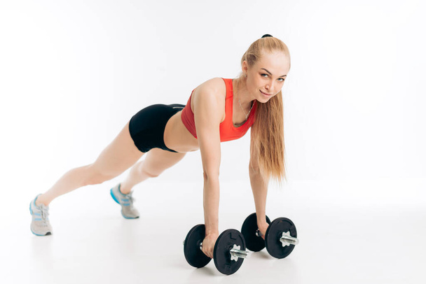 cheerful blond athlete with straight arms holding dumbbells - Foto, Imagen