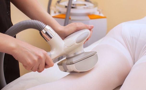 El masajista hace un masaje de hardware en las piernas del paciente en un traje blanco, de cerca en un salón de belleza. - Foto, Imagen