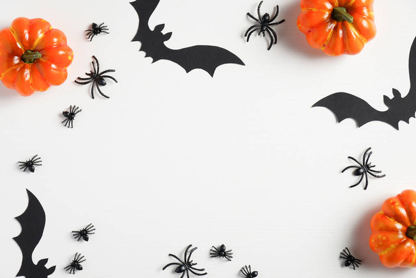 Happy halloween concept. Frame of halloween decorations, bats, spiders, pumpkins on white background. Halloween greeting card mockup, minimal style. Flat lay, top view. - Foto, Imagem