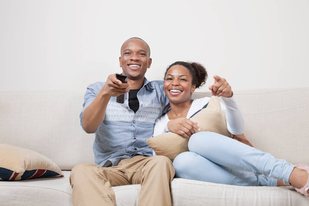 Portrait of young African American couple watching TV at home - Photo, image