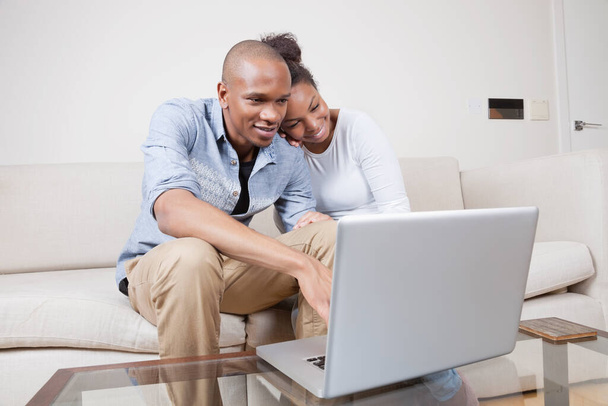 Feliz casal jovem afro-americano usando laptop em casa
 - Foto, Imagem
